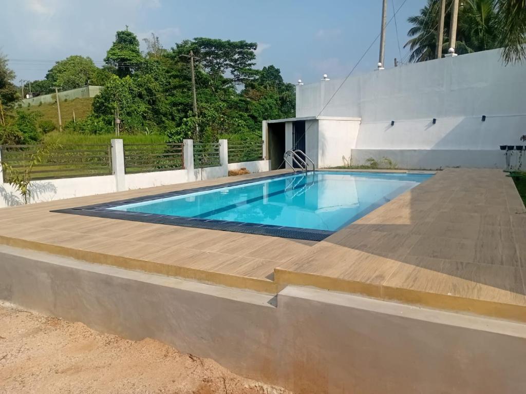 a swimming pool with a wooden deck around it at Omik Residence in Dinapamunuwa