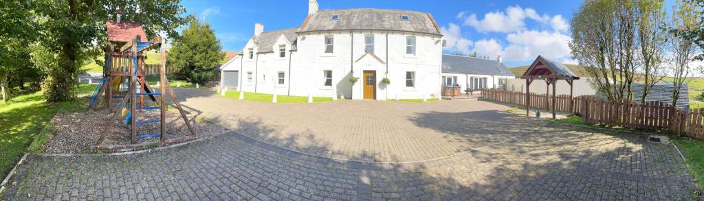a large white house with a playground in front of it at Belton House Holiday Home in Wanlockhead
