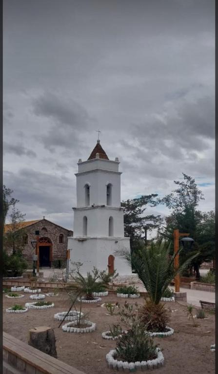 a white building with a tower in a yard at Alojamiento casa en Toconao, chile in Toconao