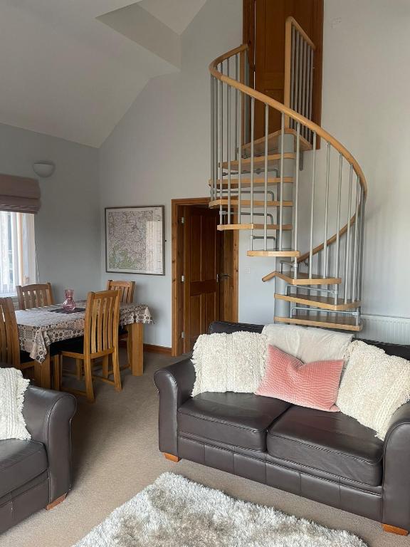 a living room with a couch and a spiral staircase at Bwlch Cottage in Gwaynynog