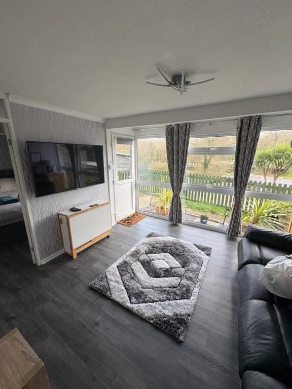 a living room with a couch and a large window at Modern retreat in Caernarfon