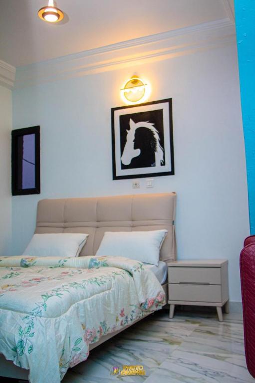 a bedroom with a bed and a white wall at La MAISON SEONE STANDARD in Abidjan