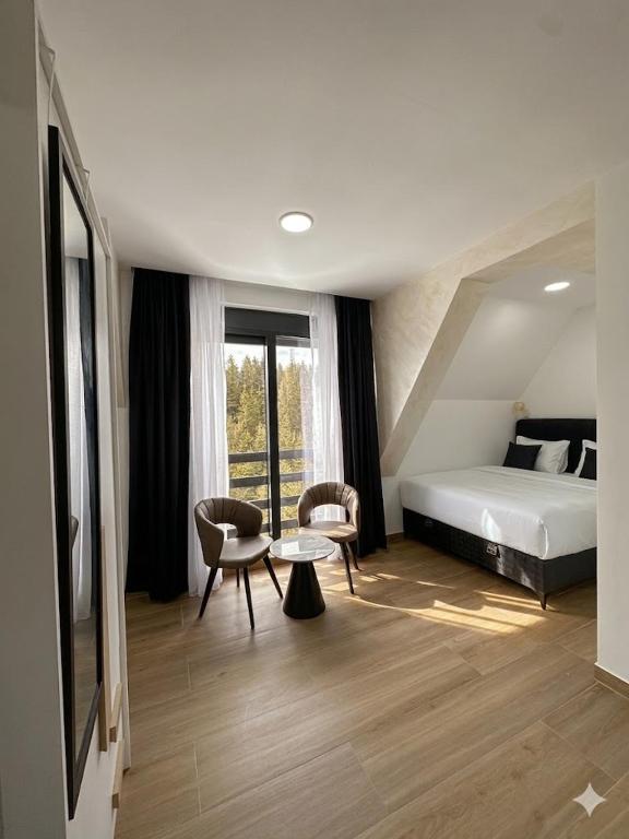 a bedroom with a bed and a table and chairs at Srebrna Jela in Žabljak