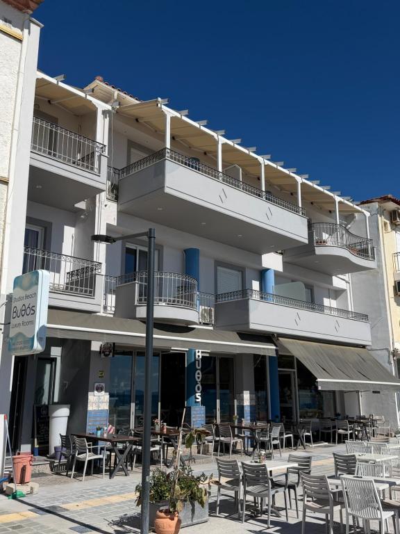 a building with tables and chairs in front of it at Vythos Rooms in Paralio Astros