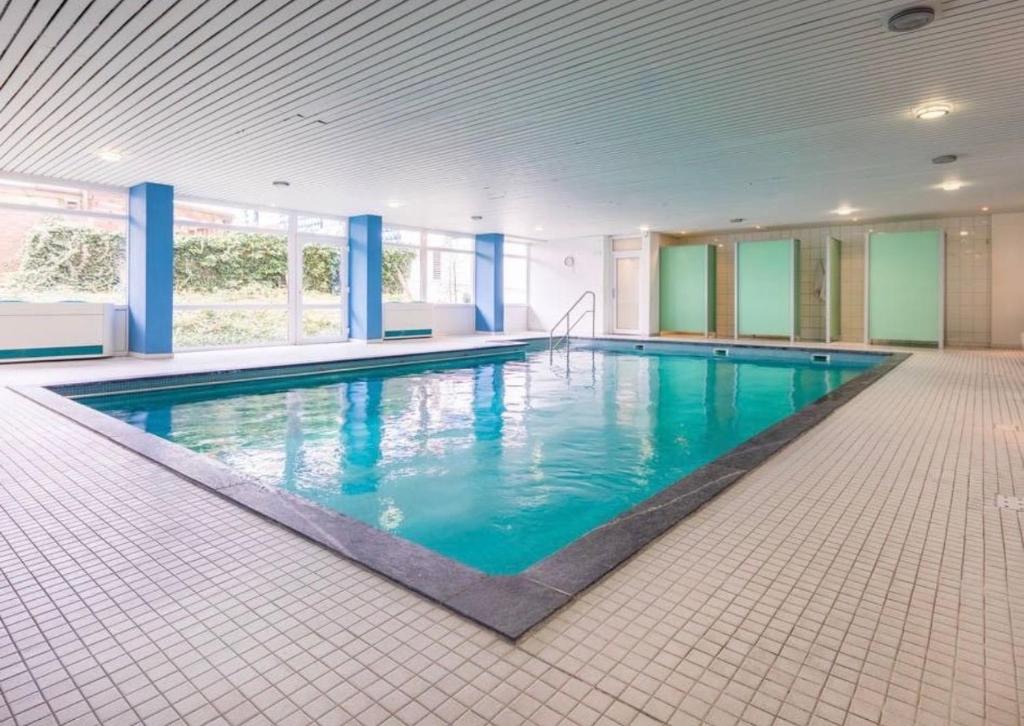 a large swimming pool with blue water in a building at Haus Iderhoff- Wohnung 5 in Norderney