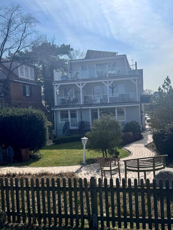 a large house behind a fence with two benches at Ostseehaus Dreesen in Timmendorfer Strand