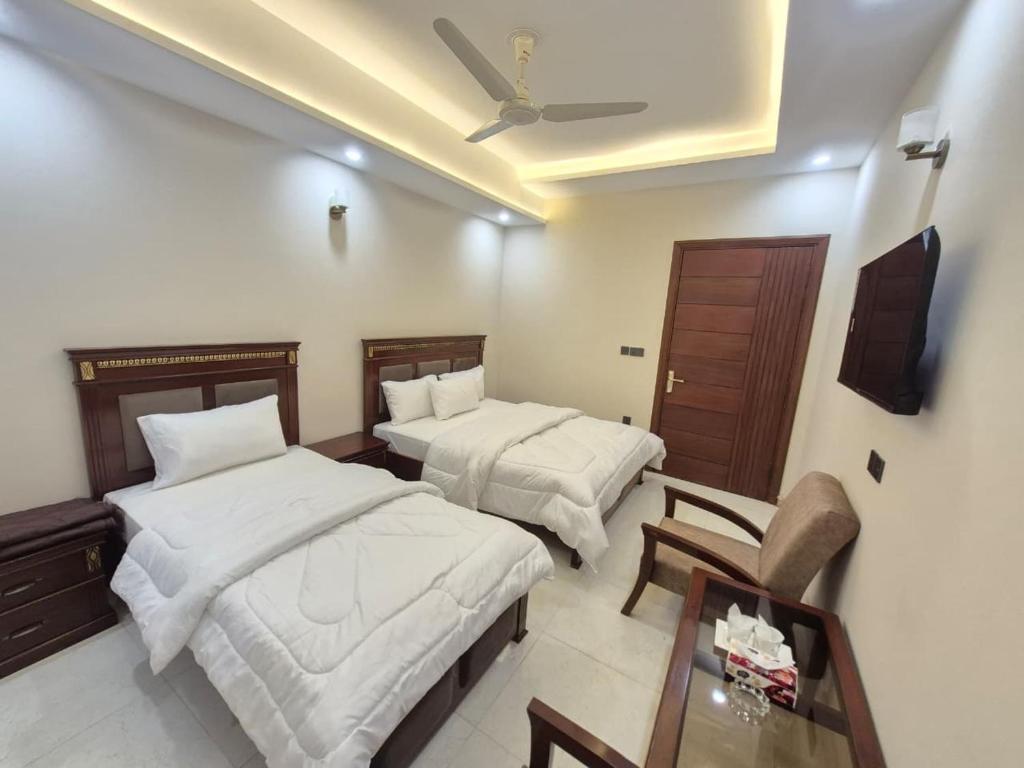 a hotel room with two beds and a table at Regency Guest House Peshawar in Peshawar
