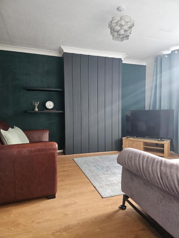 a living room with a couch and a television at Valgor -3 Bedroom House-Sleeps 5 with free parking-Ideal for contractors, families and group stays-WV6 in Tettenhall