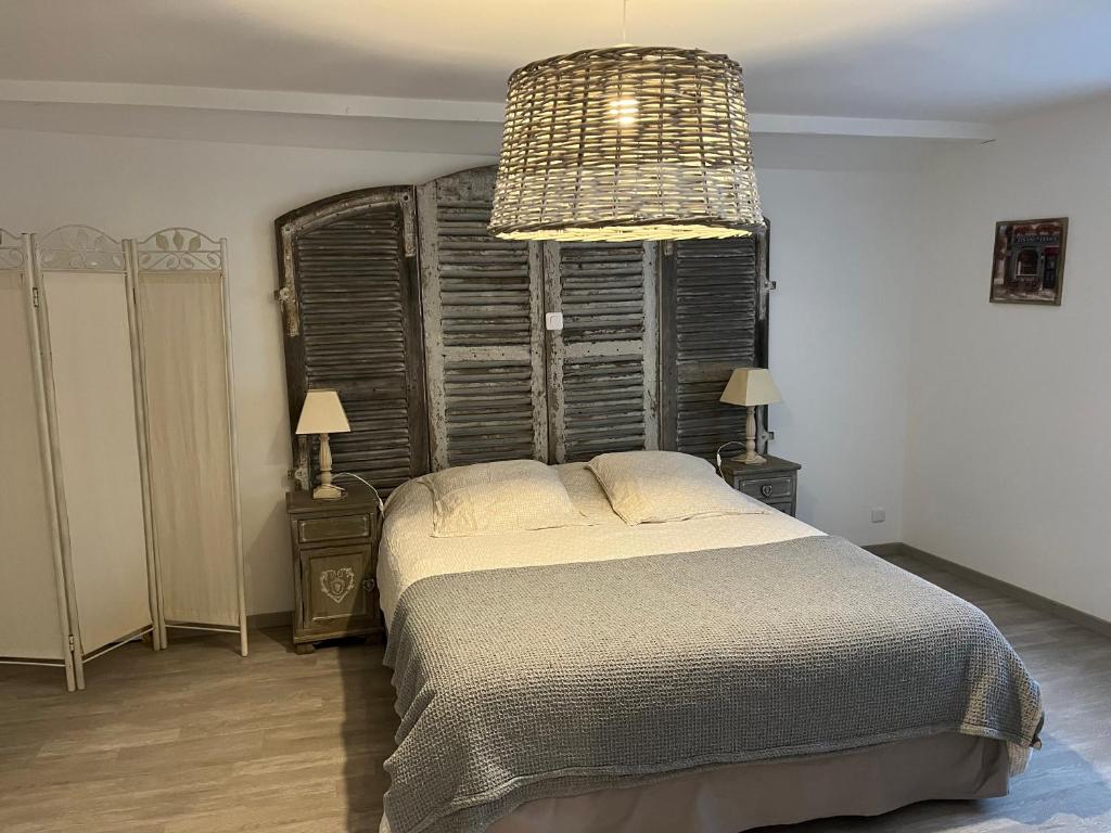 a bedroom with a large bed and a chandelier at La Maison d’Elise in Beine
