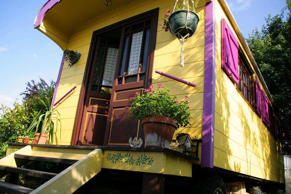 a yellow house with a potted plant on a porch at Roulotte de cirque à Rocamadour in Rocamadour
