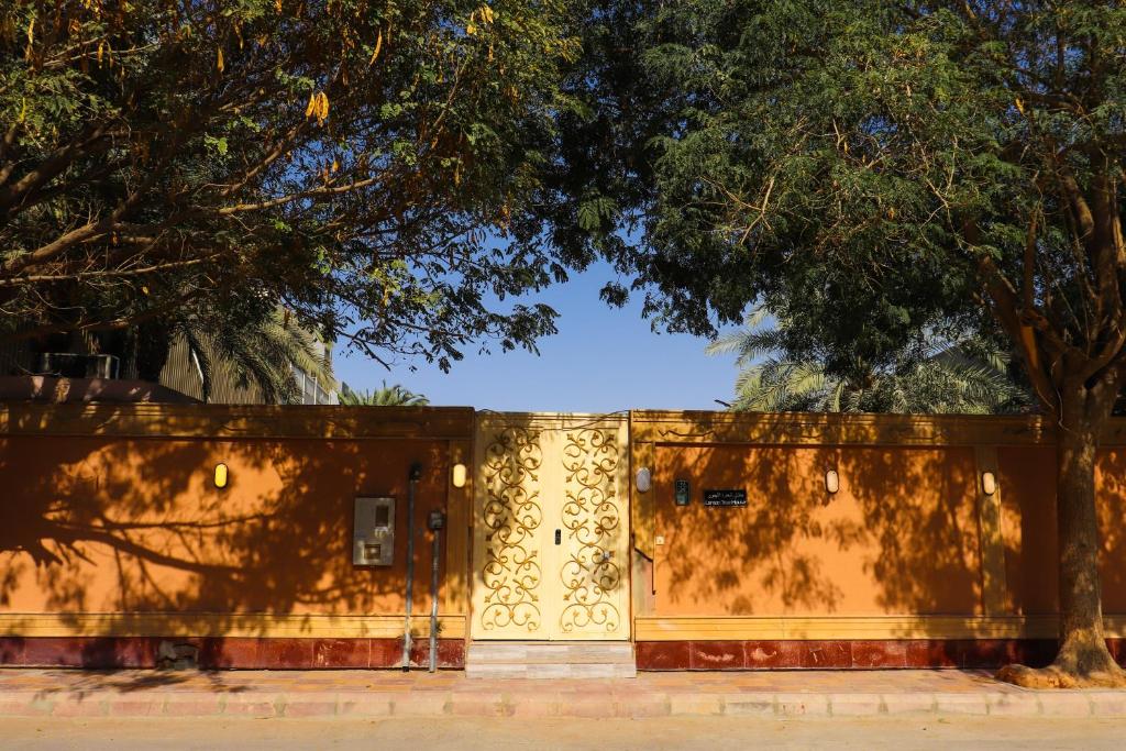 a yellow wall with a tree in front of it at Lemon Tree Guest House in Riyadh