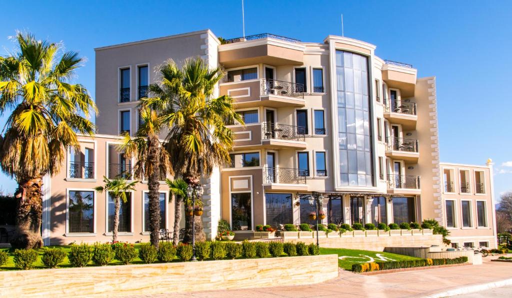a building with palm trees in front of it at Mantar Spa Hotel in Marikostinovo