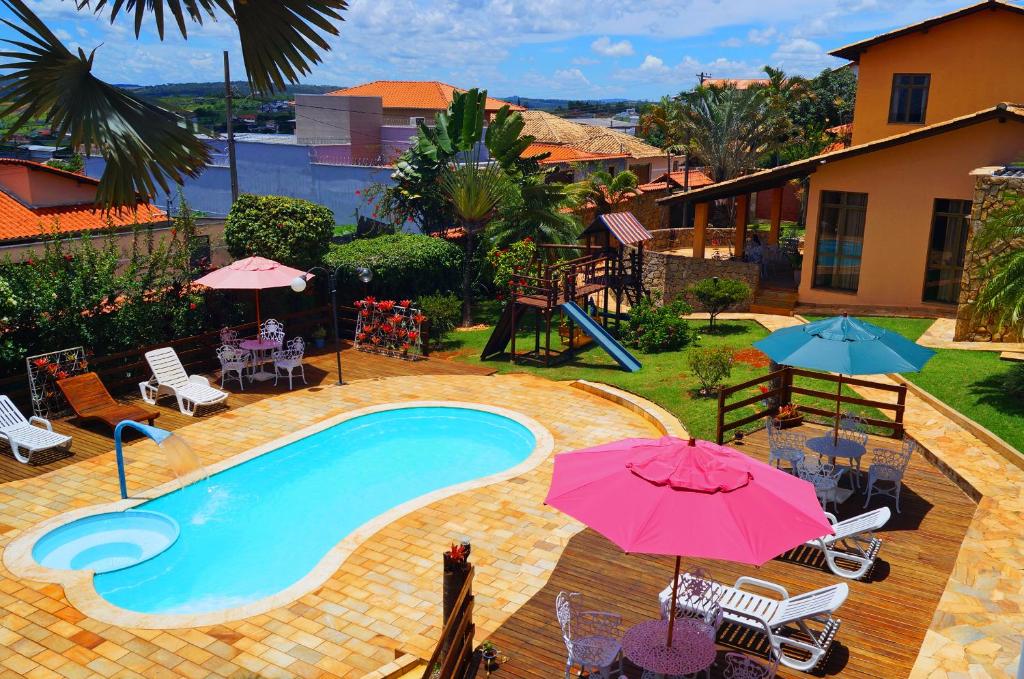 a swimming pool with umbrellas and chairs and a playground at Chalé da Serra in São João del Rei