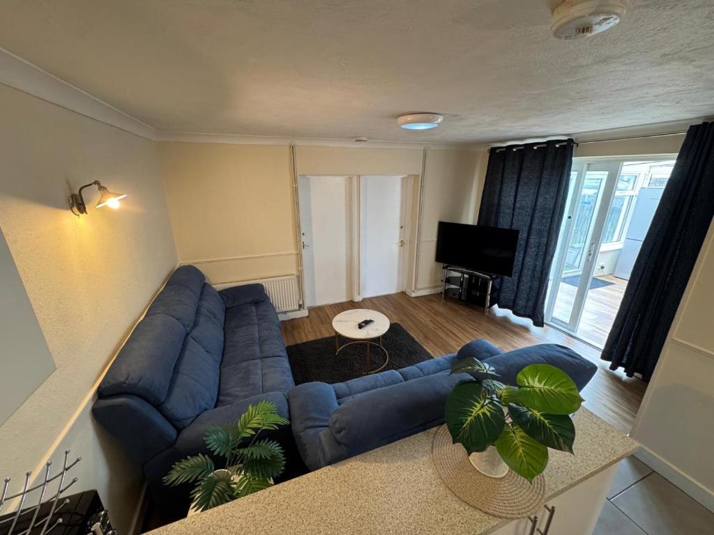 a living room with a blue couch and a tv at Amirs house in Hackington