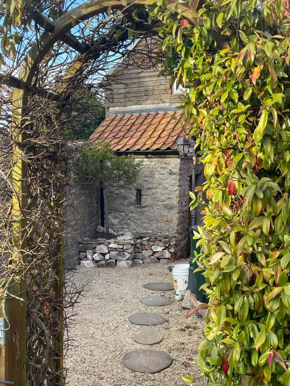 an archway leading to a stone building with a pathway at Yew Trees Barn in Backwell