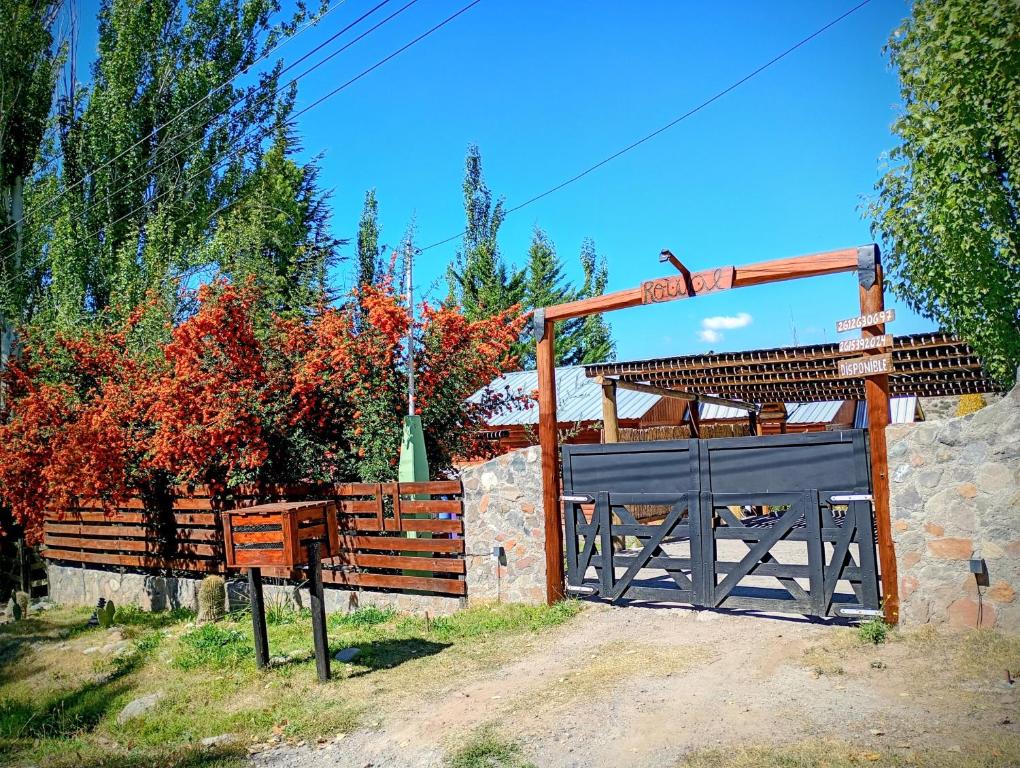 a fence with a gate and a stone wall at Cabañas Rowal Potrerillos in Potrerillos