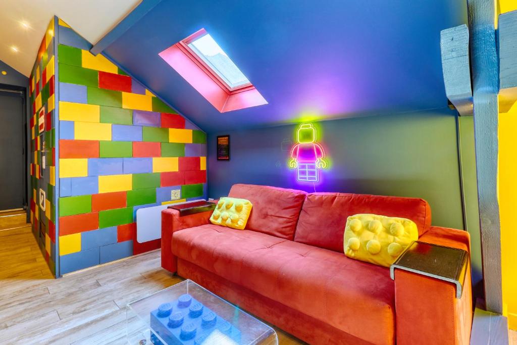 a living room with a red couch and a colorful wall at BRICKIMMERSION Suite Luxe - Cinéma Privé climatisé - Billard - Secret Room - 10min Fontainebleau - 25min Paris Ligne R in Melun