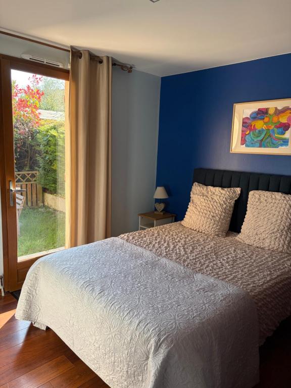 a bedroom with a bed with a blue wall at Appartement Cambita in Montévrain