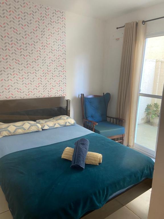 a bedroom with a bed with a blue blanket and a chair at Apto térreo, próx ao Centro, Sesi, Bioethicus, fácil acesso à Unesp in Botucatu
