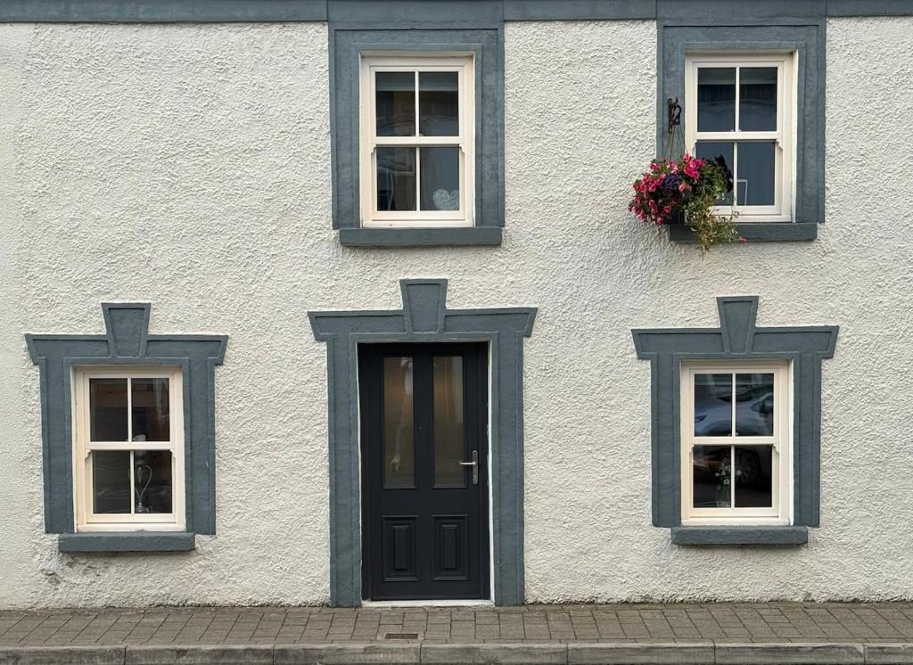 a white building with three windows and a door at Shrule Cosy Nest in Shruthair