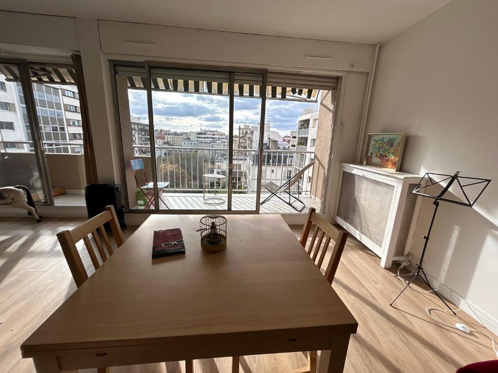 a dining room with a table and a view of a city at appartement vincennes avec balcon in Vincennes