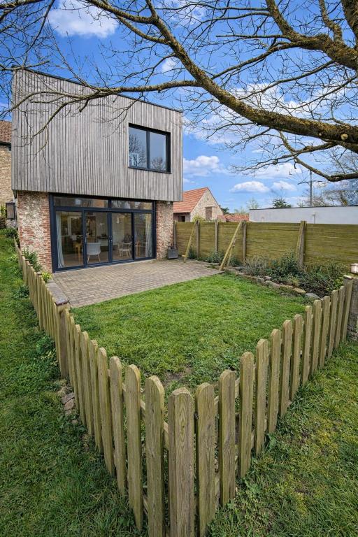 a house with a wooden fence in front of a yard at Saint Pierre Gîte in Ambleteuse
