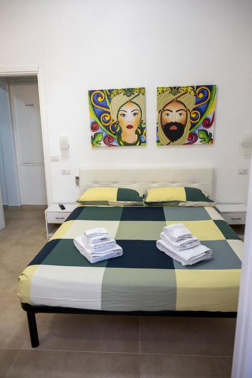 a bed in a room with two paintings on the wall at Kalsa’s House Noto in Noto