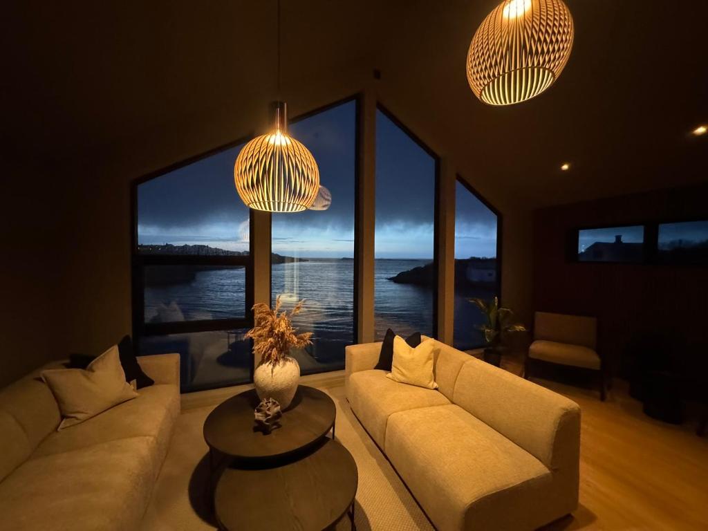 a living room with a couch and a table and windows at OceanView Karmoy Jacuzzi, Sauna & Sea Views in Karmøy