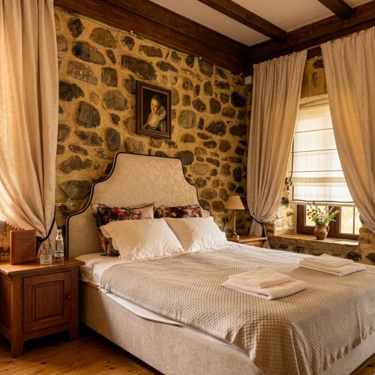 a bedroom with a bed with a stone wall at Villa Khodasheni in Kʼvemo Khodasheni