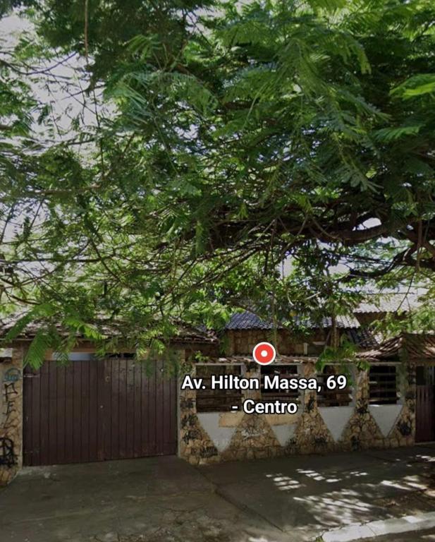a sign in front of a house with a tree at Casa da Passagem in Cabo Frio