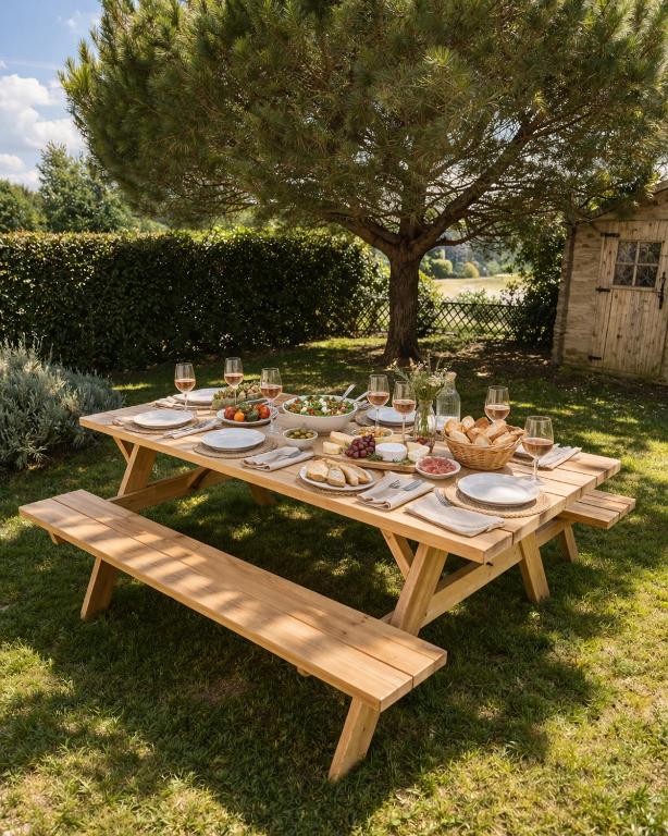 a wooden picnic table with food and wine glasses at L Echappee Jardin prive proche plage Sainte Cecile in Camiers