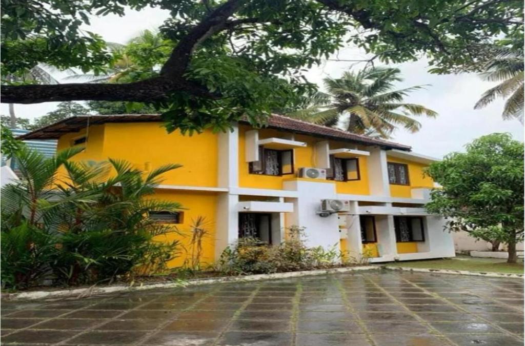 a yellow and white house with a tree at The Boho Inn in Cochin