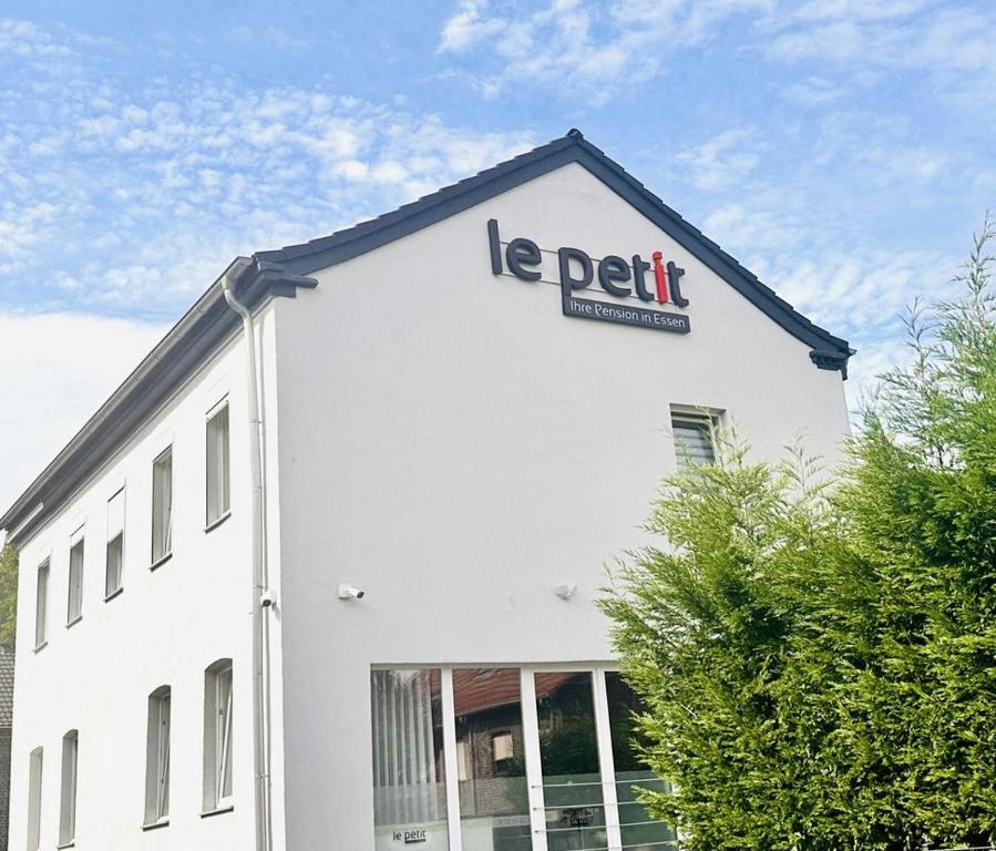 a white building with a sign on the side of it at Le Petit - Ihre Pension in Essen in Essen