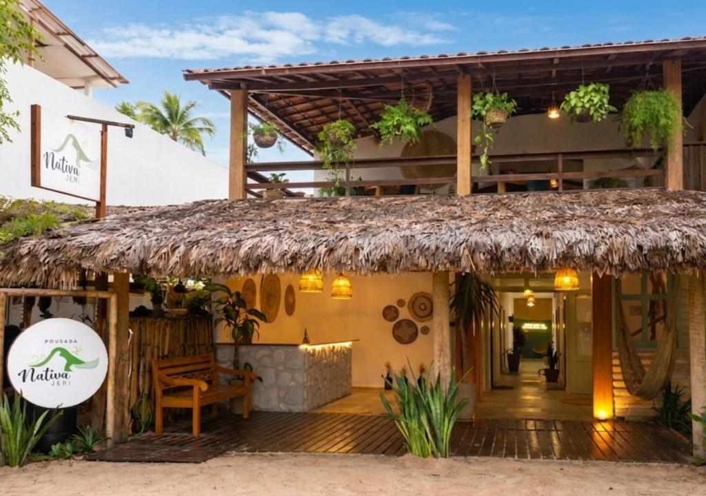a restaurant with a thatched roof on a beach at Pousada Nativa Jeri in Jericoacoara