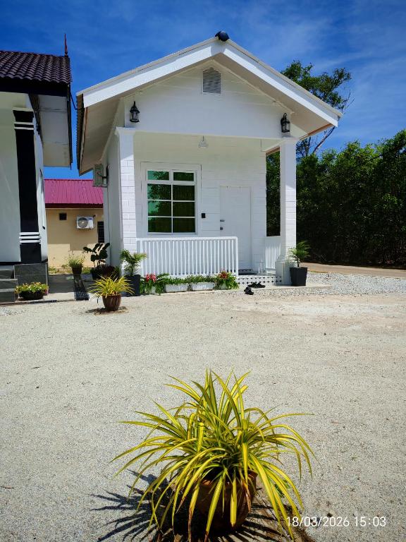 a white house with a plant in front of it at Zaifaa Beach Inn in Setiu
