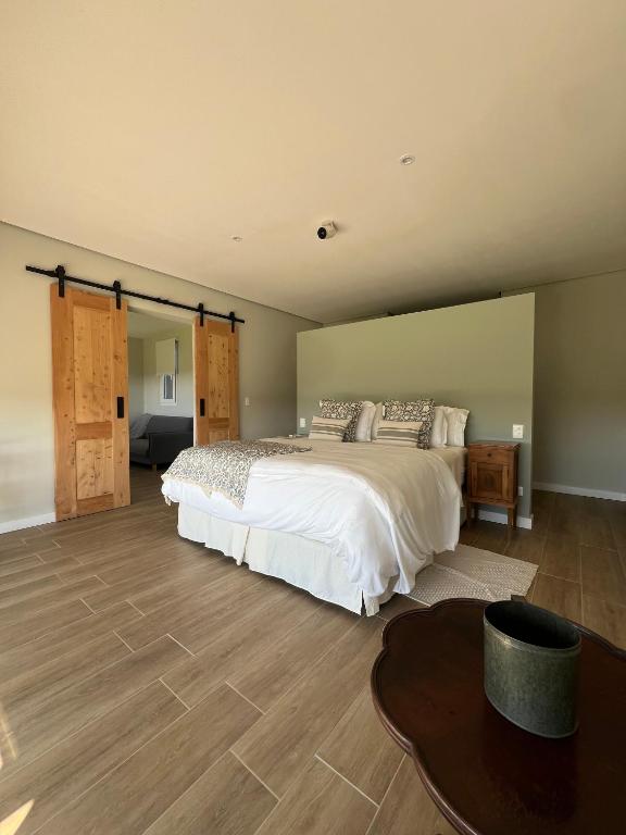 a bedroom with a large white bed and a table at Buenos Vientos Casa de Campo in Maldonado