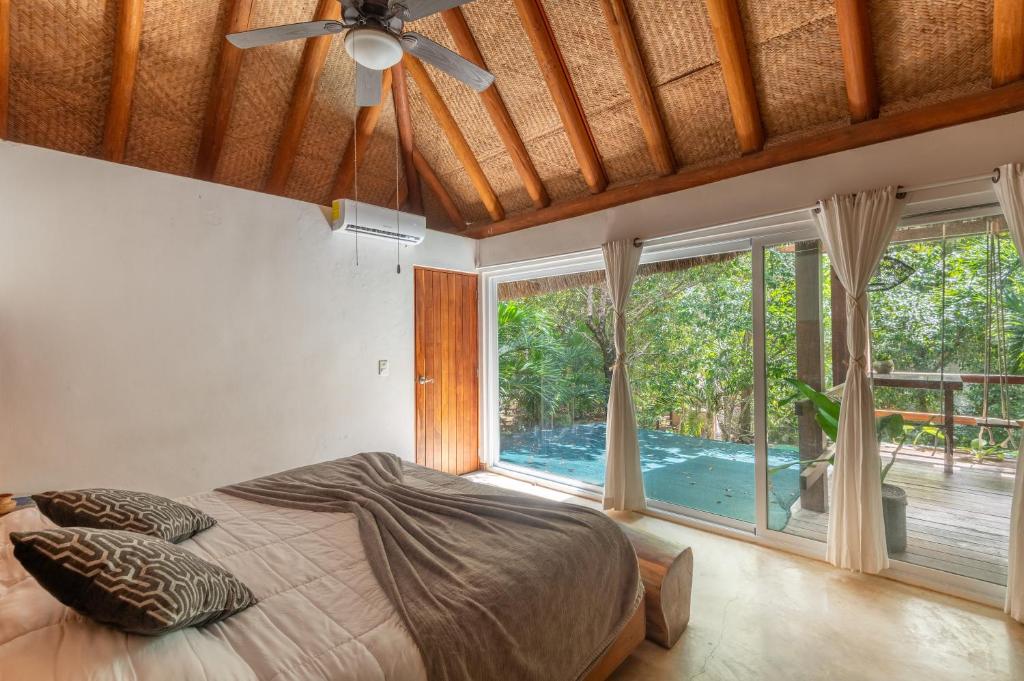 a bedroom with a bed and a large window at Luxury Jungle Suite with Private Jacuzzi & Cenote Pool View in Chemuyil