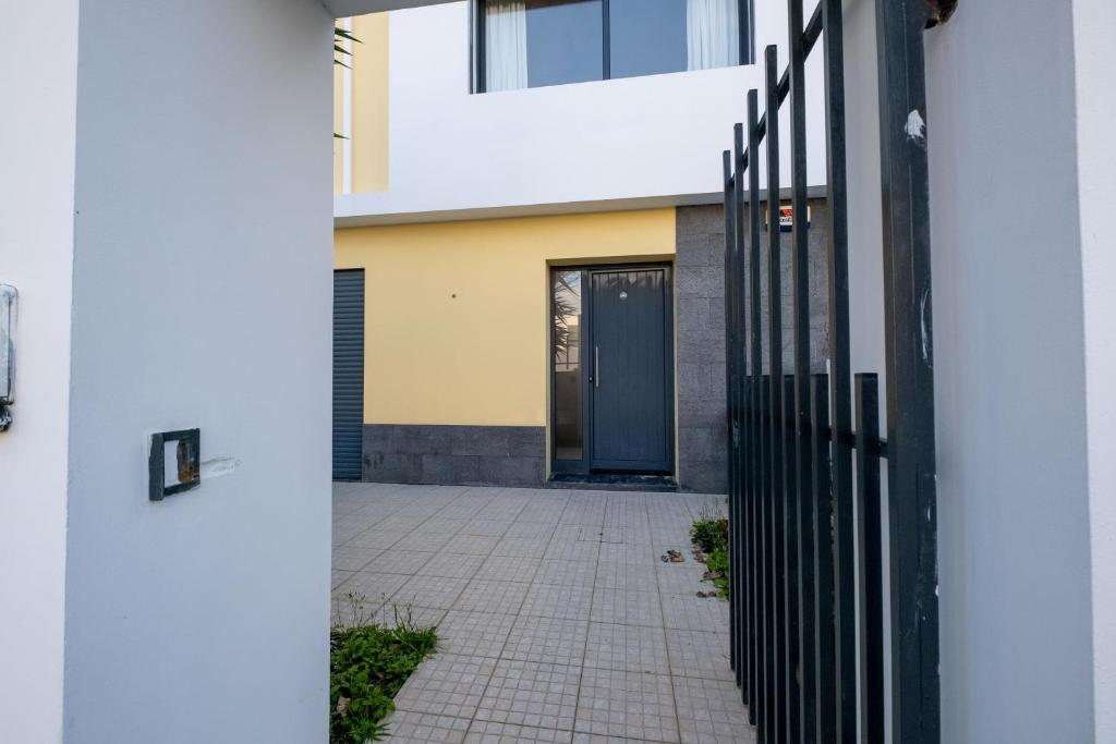 a gate in front of a house with a blue door at A casa da Girafa in Ponta Delgada