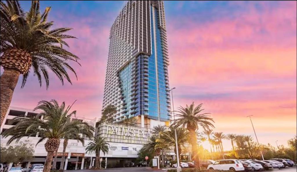 a tall building with palm trees in a parking lot at Palms Place Condo with strip view in Las Vegas