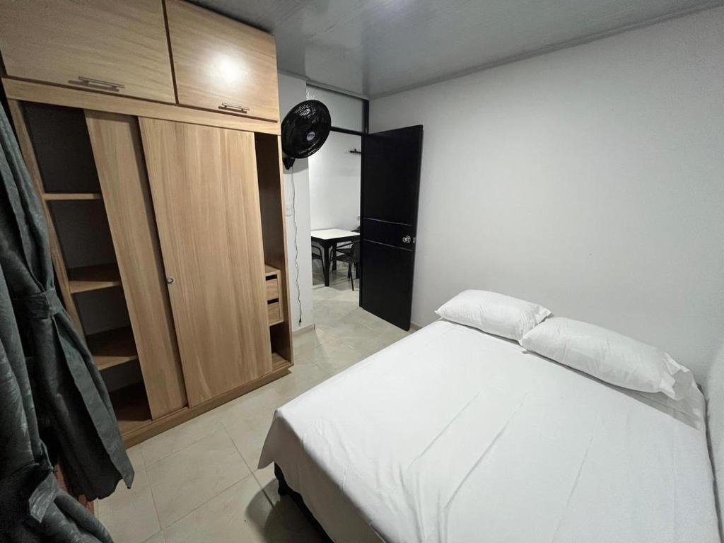 a bedroom with a white bed and a wooden cabinet at El Rincon de Teresita in Villavicencio