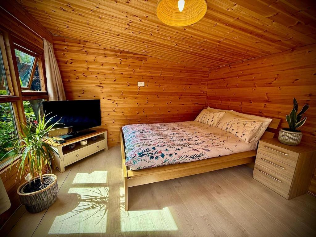 a bedroom with a bed and a flat screen tv at Glebe Summer House in Osmington