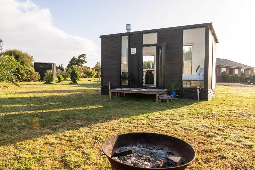 a tiny house with a fire pit in the yard at The Nest at Arahura Escape by Tiny Away in Kaihinu