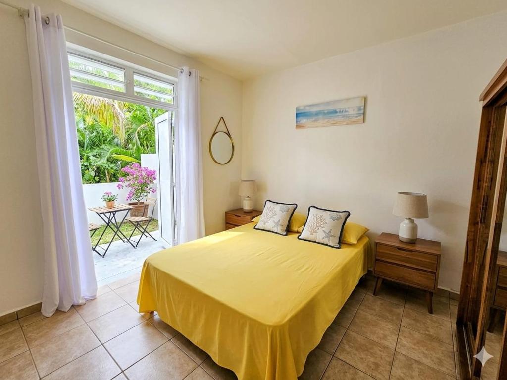 a bedroom with a bed with yellow sheets and a window at Orchidée in Capesterre-Belle-Eau