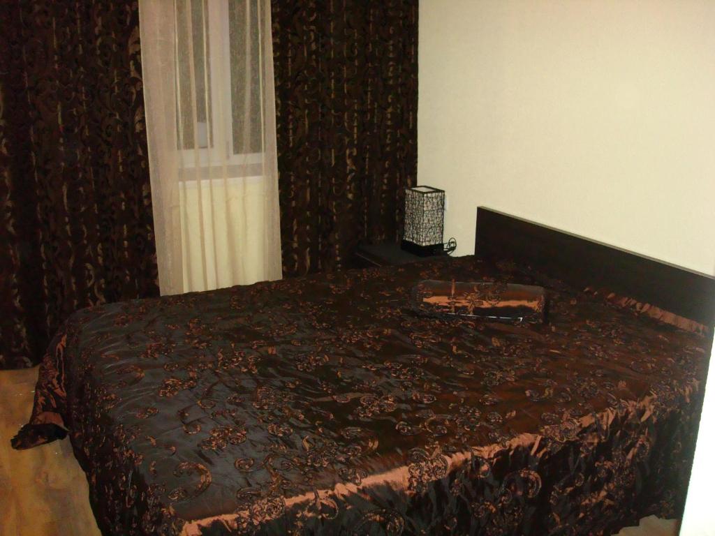 um quarto com uma cama com um cobertor castanho em Отель Гармония em Dnipro