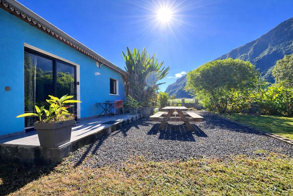 a picnic table in front of a blue house at Le Refuge d'Heva in Salazie