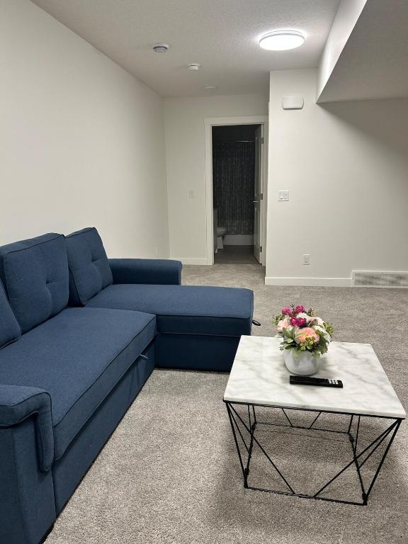 a living room with a blue couch and a table at Lizzy cozy Basement suite in Airdrie