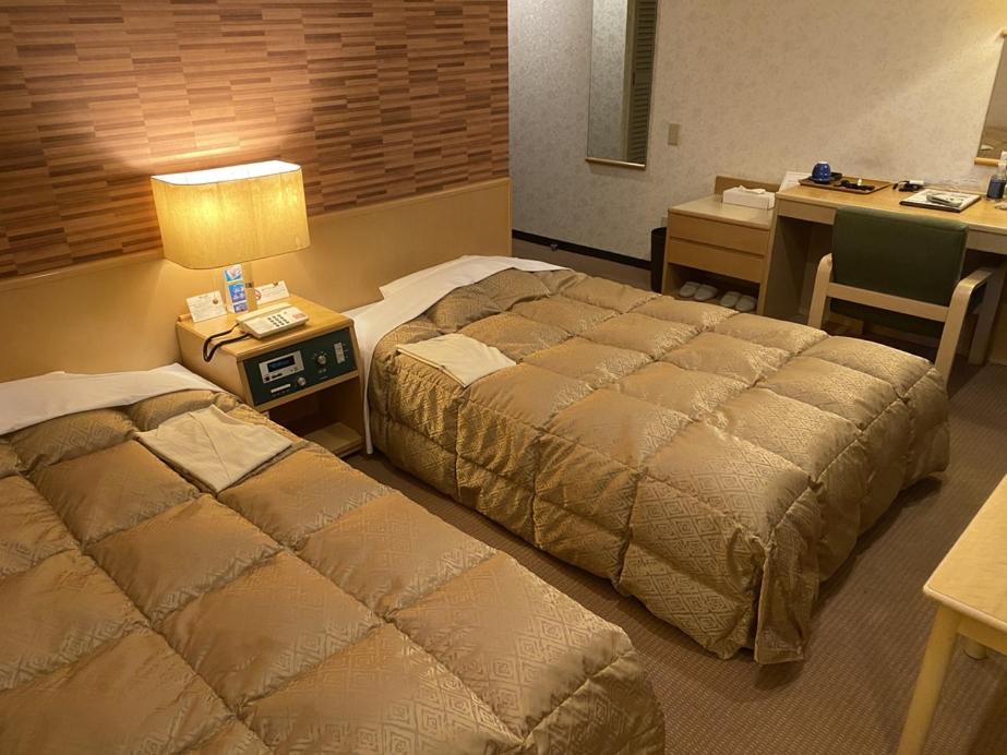 a hotel room with two beds and a desk at Kuji Grand Hotel in Kuji