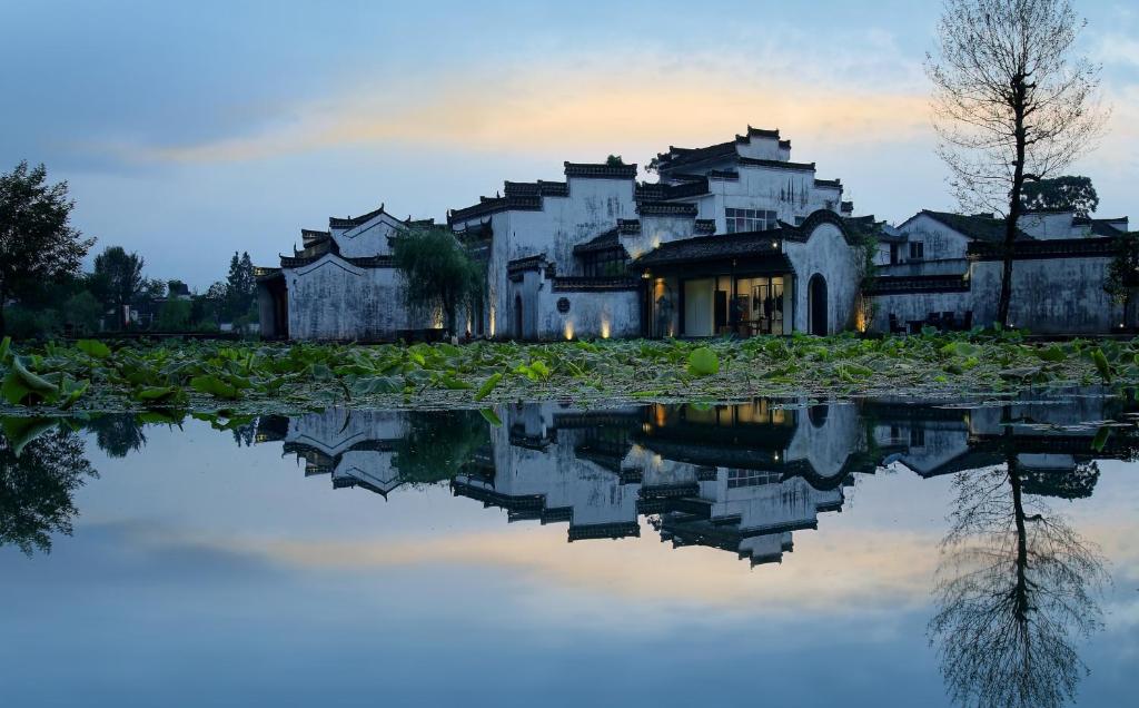 a house with its reflection in a body of water at Huangshan Chenkan Su House Hotel in Chengkan