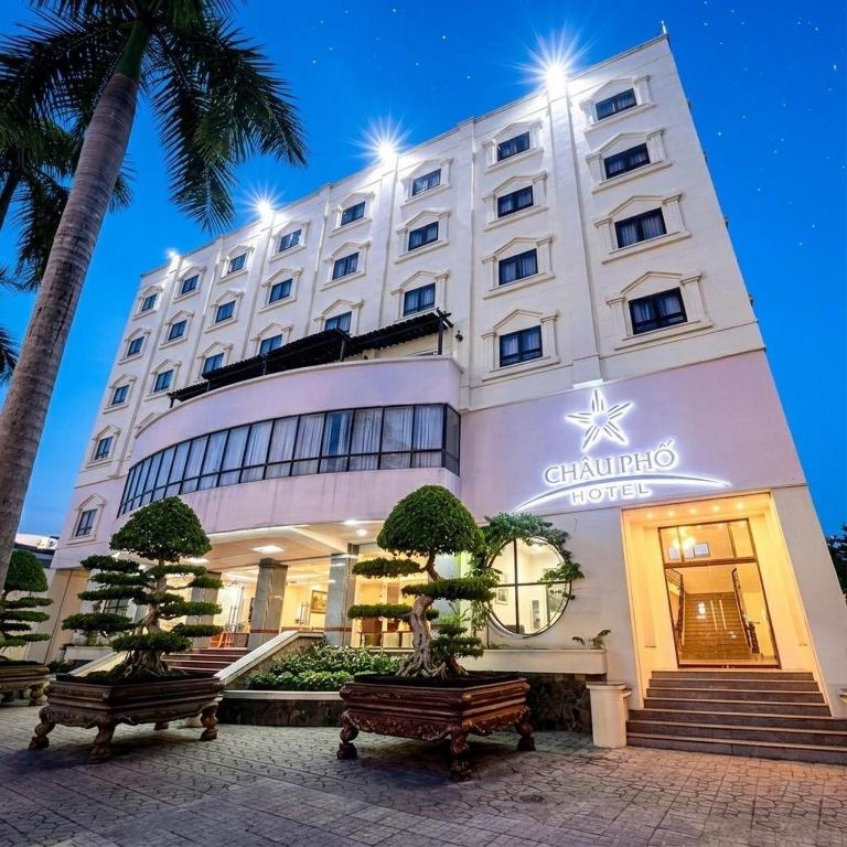 a hotel with two benches in front of a building at Chau Pho Hotel in Chau Doc