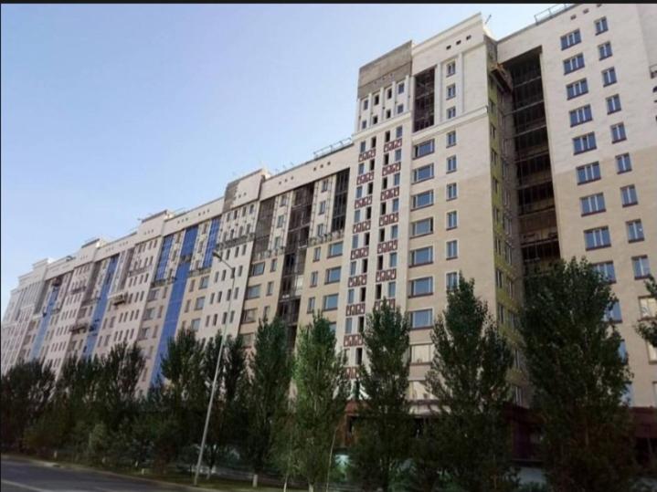 a large white building with trees in front of it at Уютные комнаты-студии in Astana